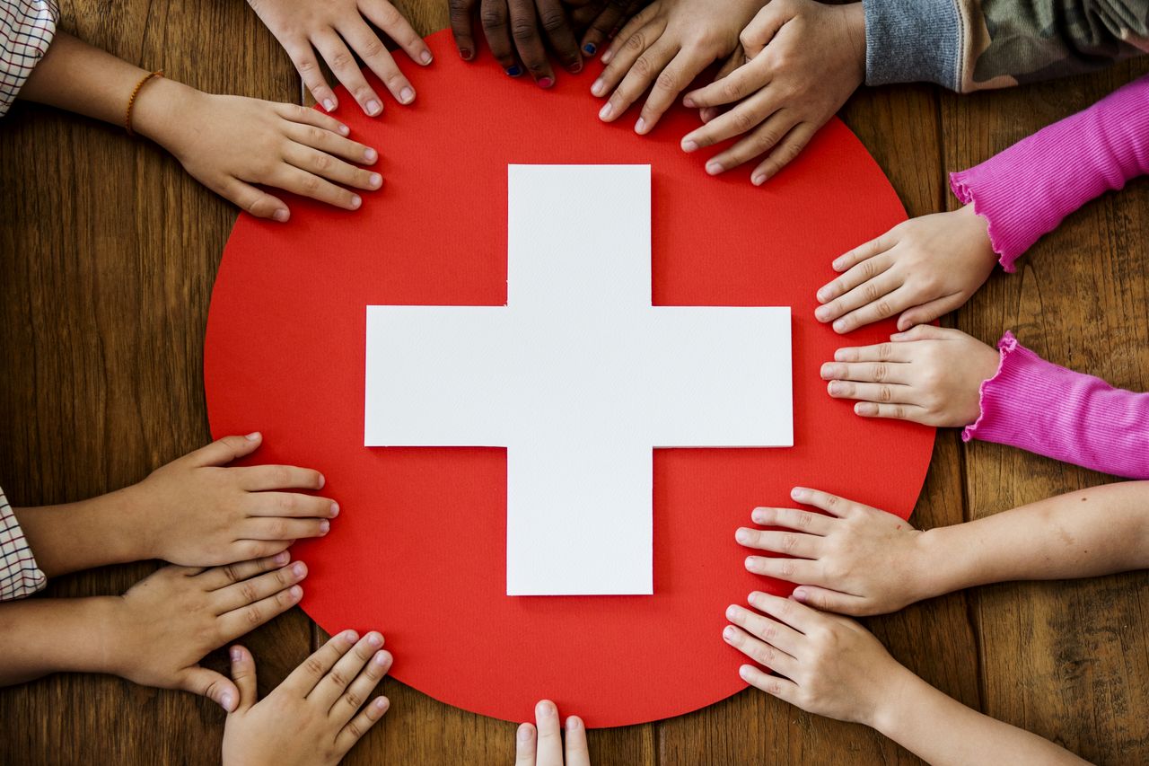 Des mains d'enfants entourent un symbole de santé rouge et blanc